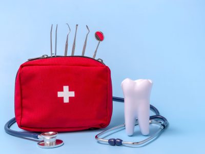 a model of a tooth, a stethoscope, a dentist's tool, a first aid kit. concept first aid for toothache